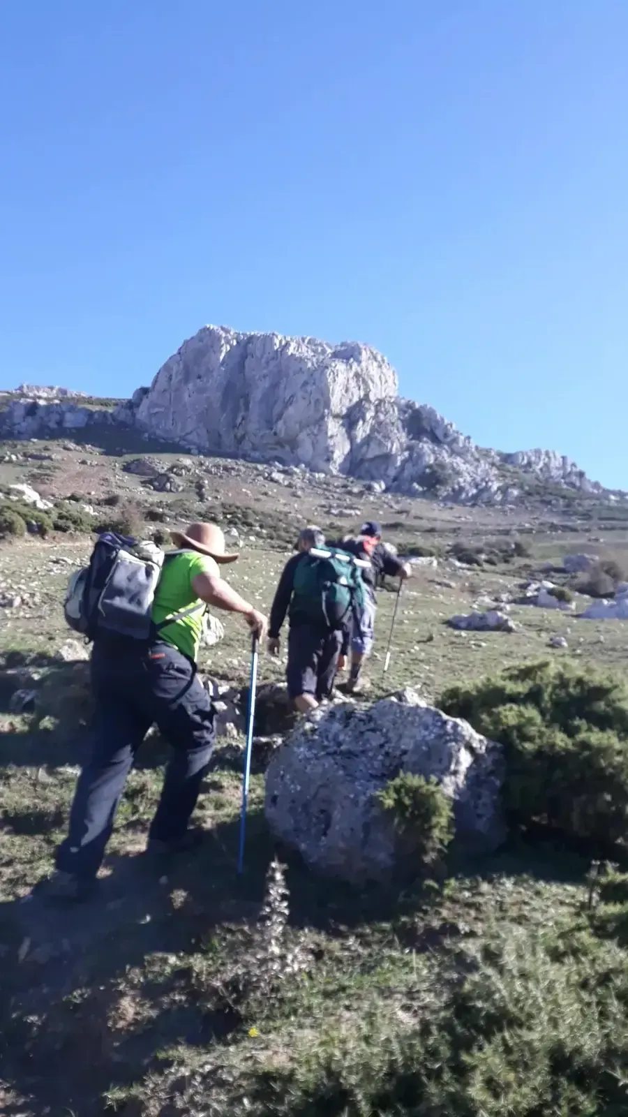 Hikers climbing a rocky path towards a limestone summit
